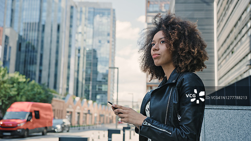 混血女人在市中心用手机APP打优步图片素材