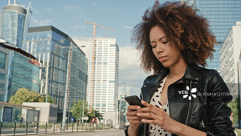 混血女人在市中心用手机APP打优步图片素材