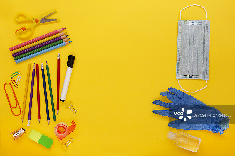 黄色背景上的学校和办公用品及新冠病毒防护用品图片素材