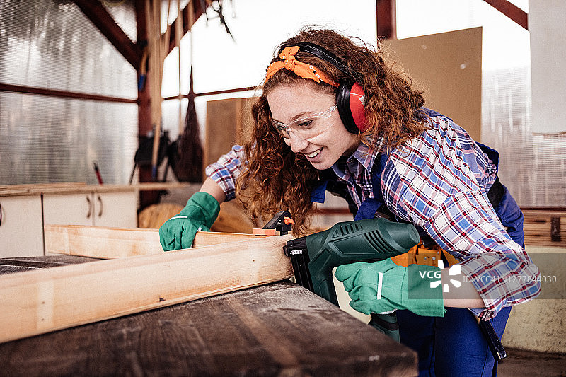 年轻女木匠使用射钉枪工作图片素材