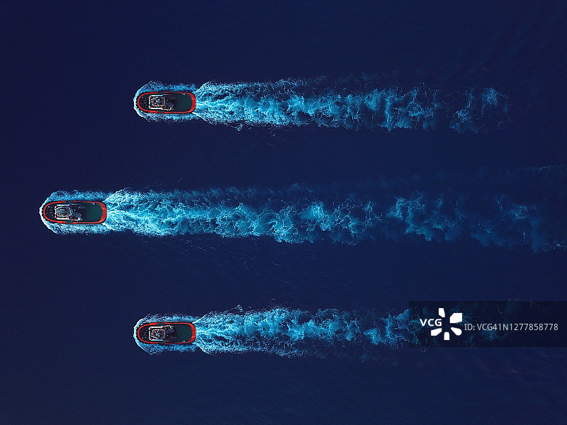 深蓝色海水中三艘移动拖船的航拍俯视图图片素材