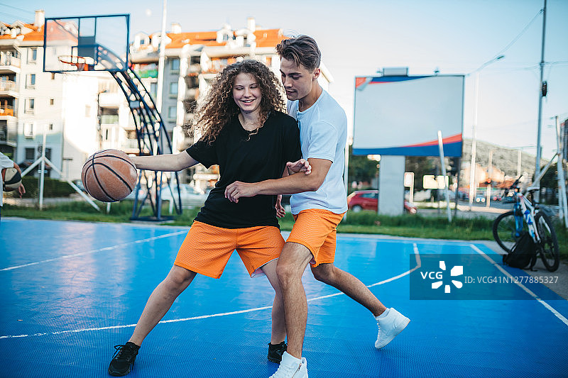 年轻男人和女友在篮球场上玩耍图片素材