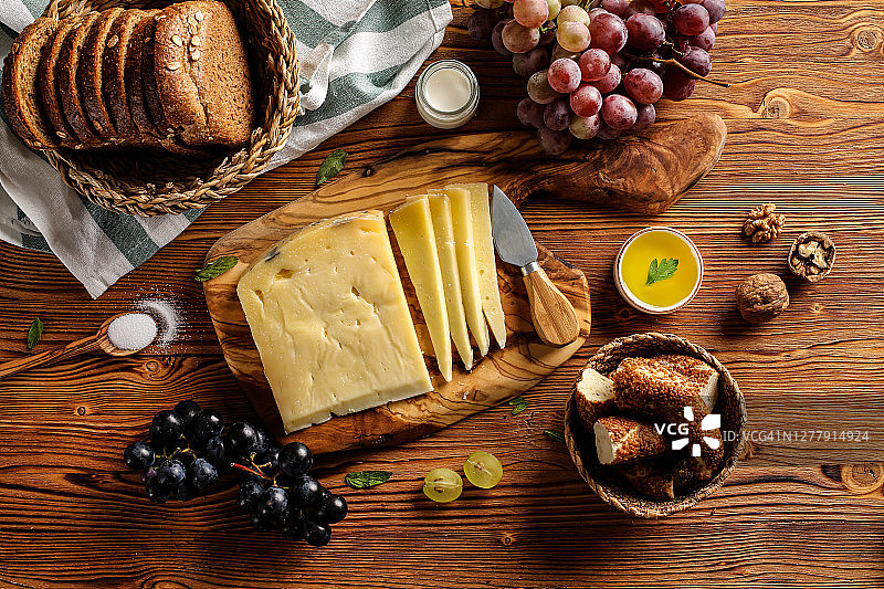 木桌上的格鲁耶尔奶酪与木制砧板、刀具图片素材