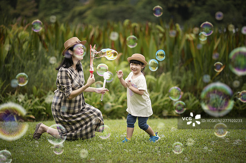 在公园里和女儿一起吹泡泡的中国孕妇图片素材