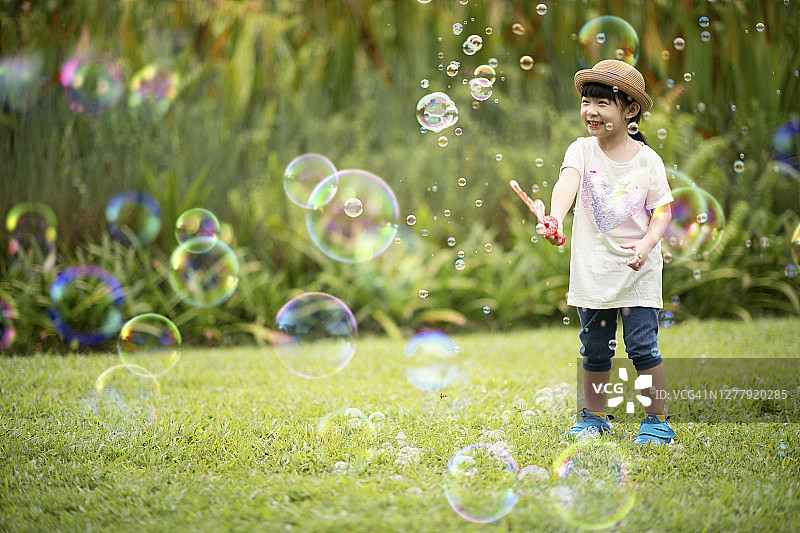 中国亚洲年轻女孩在公园吹泡泡玩耍图片素材