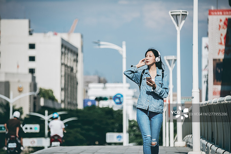 女人在街上边走边使用智能手机图片素材