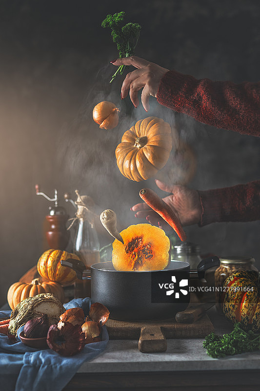 创意南瓜汤静物：飞溅的蔬菜配料、蒸煮锅和女人手图片素材