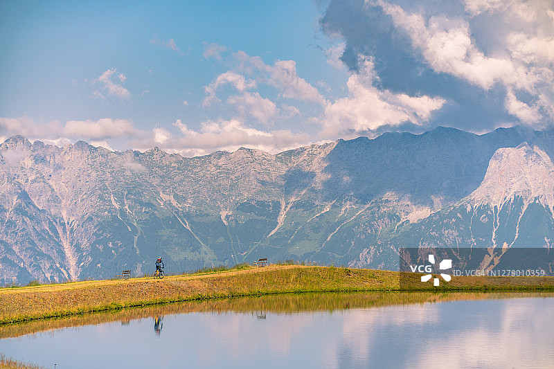 在奥地利阿尔卑斯山湖边骑自行车的男人图片素材