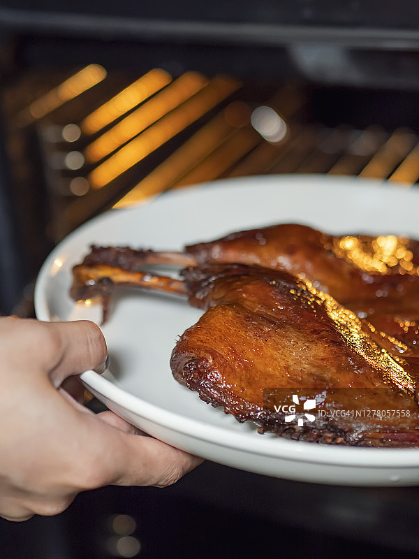 女人将腌制好的鸭子放入烤箱图片素材