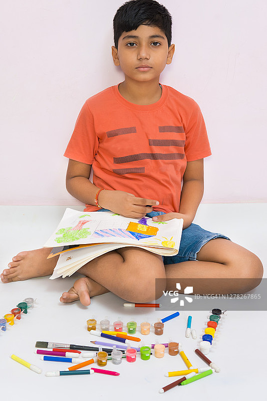 男孩画彩色的房子并看着镜头图片素材