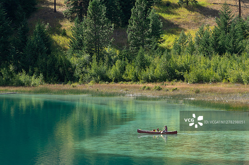 一家人在壮丽的山地湖泊上划独木舟图片素材