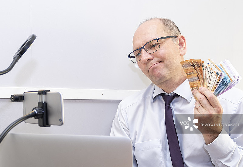 喜悦的心情：白人男子手持大量欧元钞票，欣喜不已图片素材