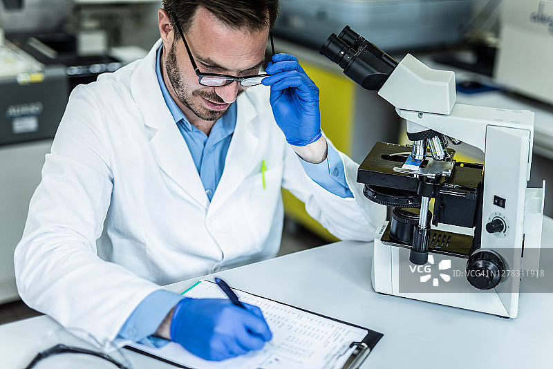 中年科学家使用显微镜记录测试结果图片素材