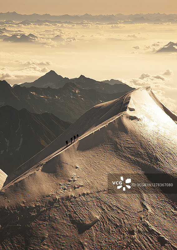 日出时分雪岭上的登山者图片素材
