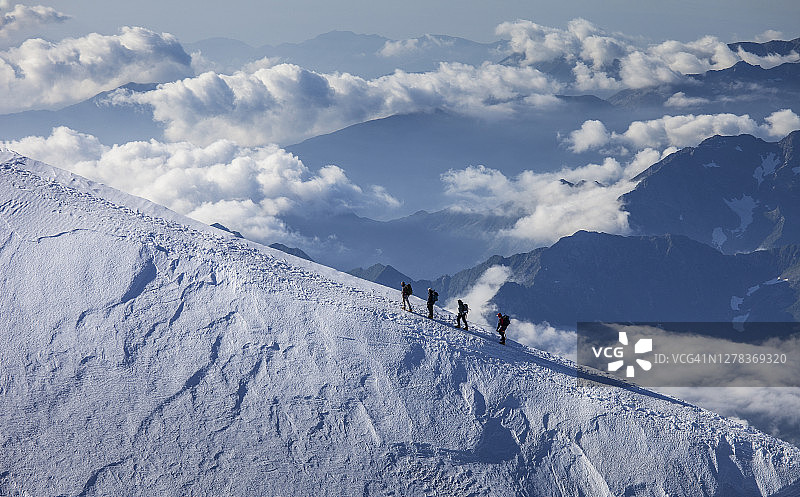 云层之上雪脊上的攀登者图片素材