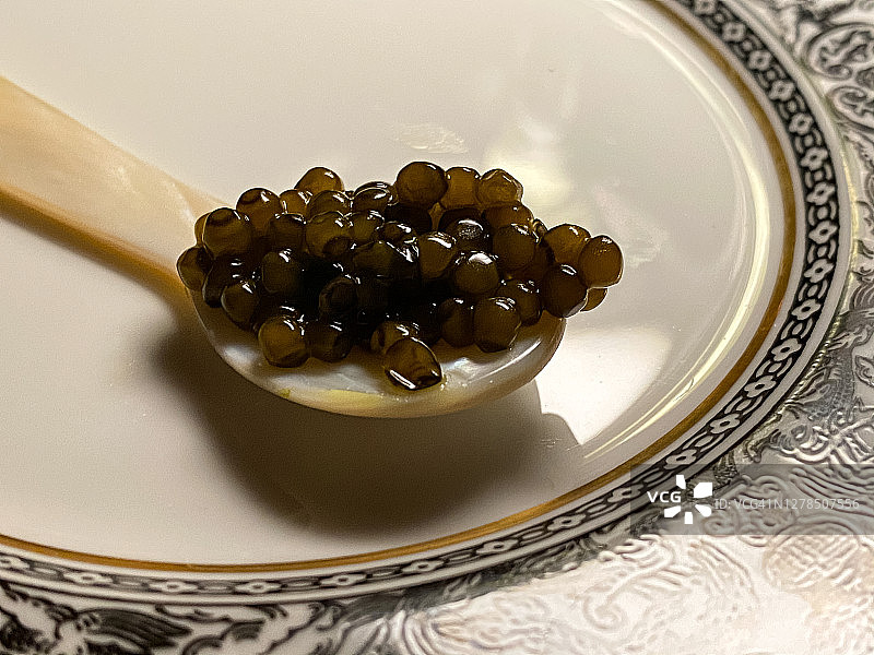 精致的，少量的混合鱼子酱放在优雅的珍珠母勺上，放在瓷盘上图片素材