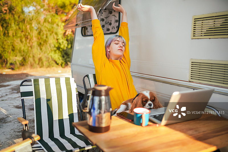 年轻女人在露营时使用笔记本电脑喝咖啡图片素材