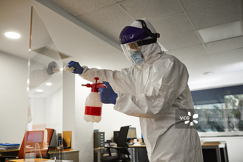 身穿防护服的男人正在消毒屏幕隔板图片素材