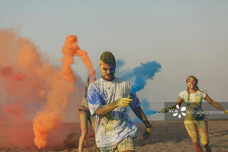 在海滩上使用彩色烟雾弹进行节日庆祝图片素材