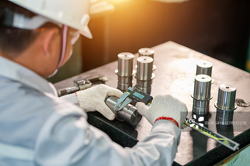 工人用数显游标卡尺测量不锈钢物体图片素材