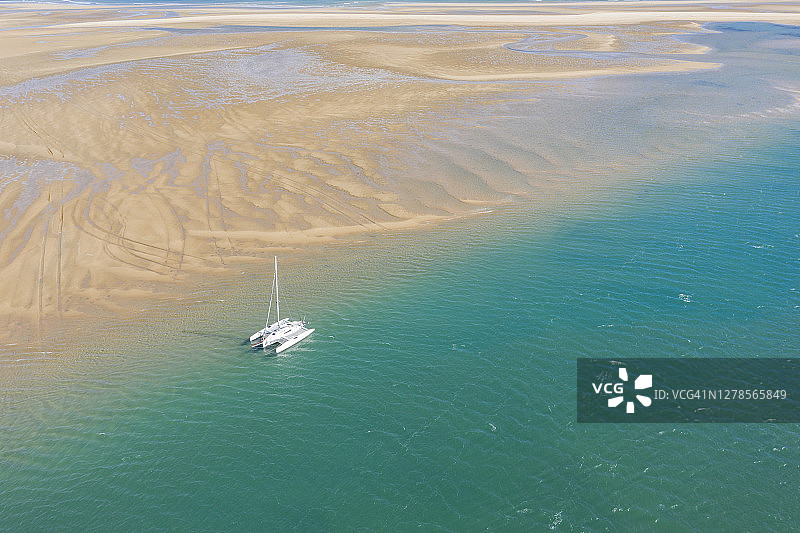 无人机视角：停泊在沙洲旁的单桅游艇，湛蓝的海水图片素材