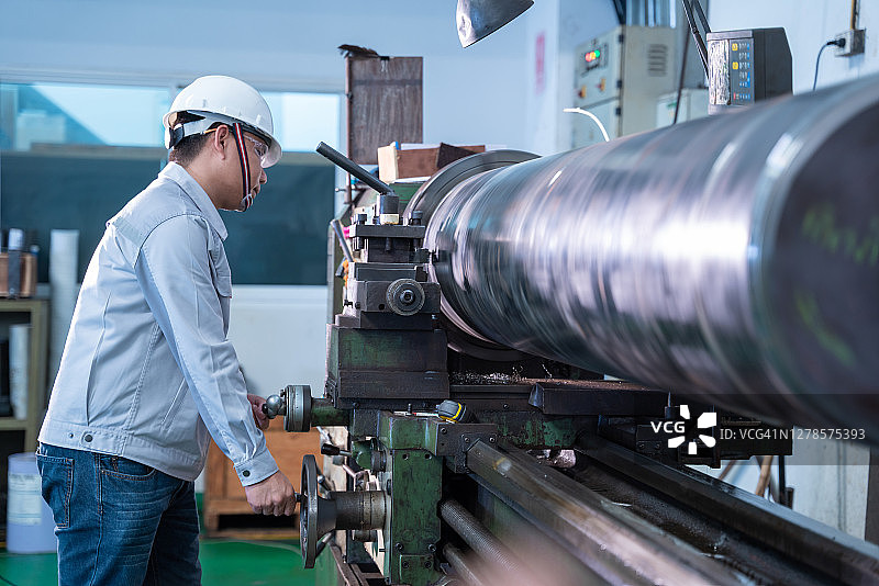 身穿安全制服的亚洲工人在金属工业工厂操作手动车床图片素材