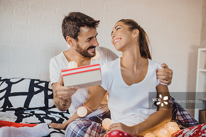 节日期间，情侣在床上互赠圣诞礼物图片素材