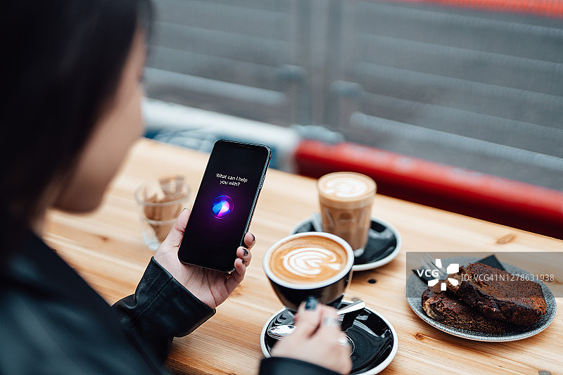 在咖啡馆使用智能手机助手功能的年轻女人图片素材