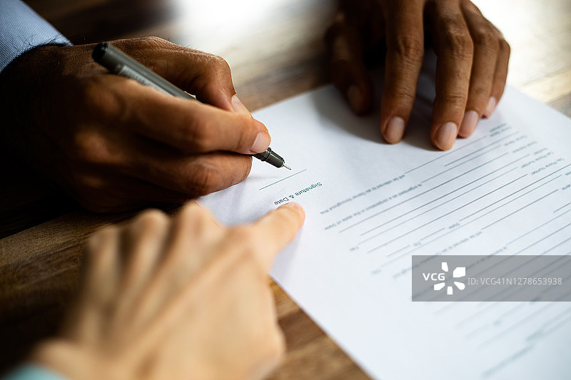 男人在办公室签署合同，女人在纸上指点图片素材