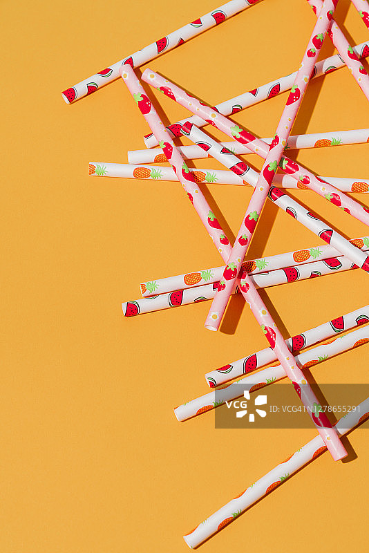 橙色背景上的纸质吸管图片素材