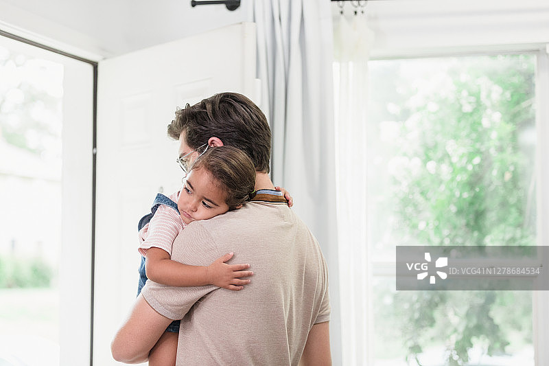 年轻的居家爸爸安慰着悲伤的学龄前女儿图片素材