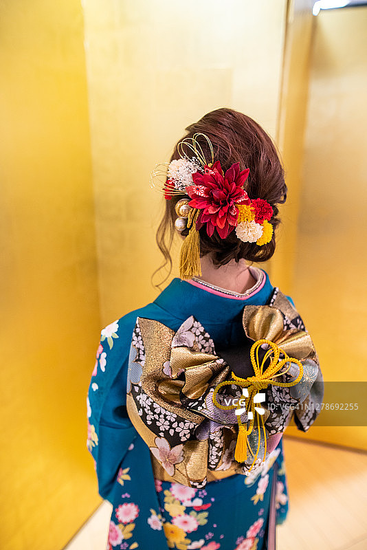 身穿和服的年轻女子站在金色屏风前参加成人礼的背影图片素材