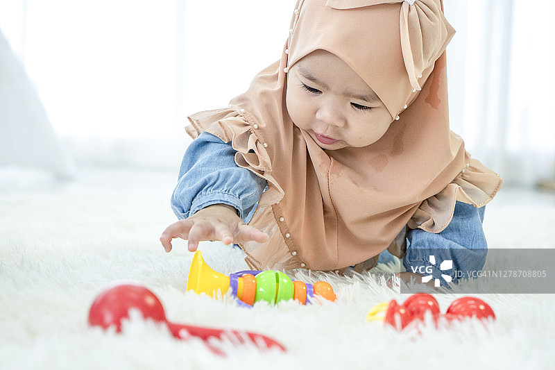在床上爬行和翻滚的可爱女婴图片素材