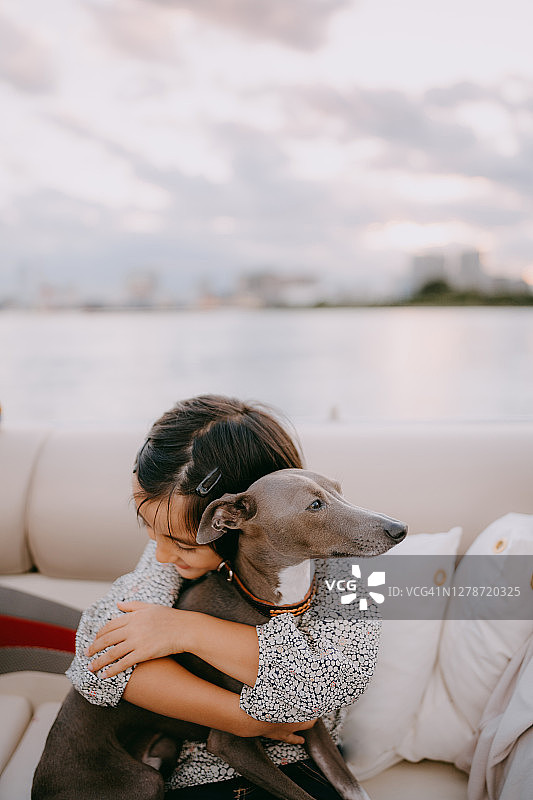 在船上拍打狗的可爱年轻女孩图片素材