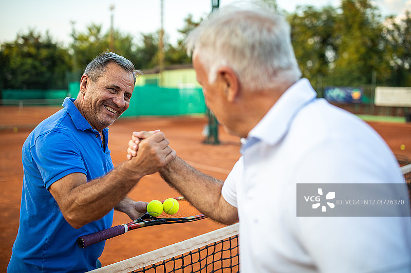 两个快乐的老年朋友在网球场上一起玩耍图片素材