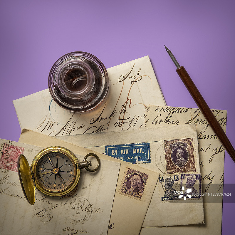 紫色背景上的古董墨水瓶和旧信件图片素材