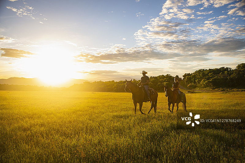 美国犹他州塞勒姆，日落时分骑马的父亲和女儿（14-15岁）图片素材