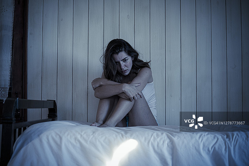 坐在床上的悲伤年轻女人图片素材