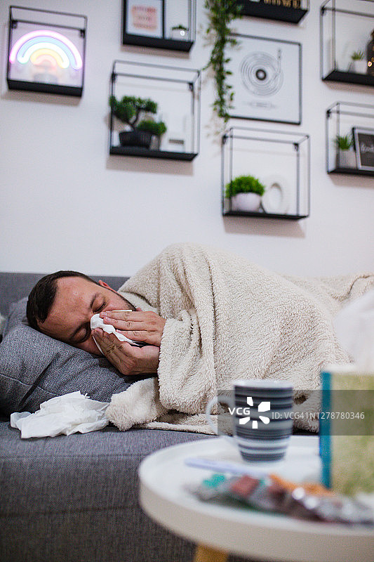 生病男人卧床擤鼻涕图片素材