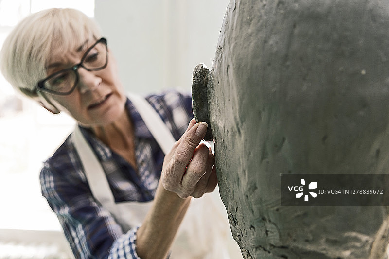 制作粘土半身像耳朵的年长雕塑家图片素材