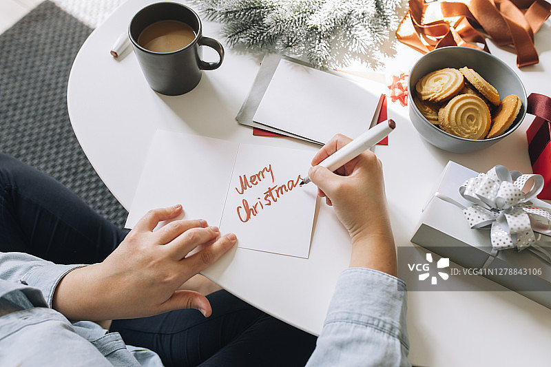 圣诞节快乐：一位快乐的女士正在为亲人写圣诞贺卡图片素材
