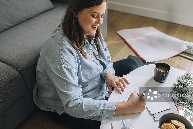 圣诞快乐：快乐的女人写圣诞贺卡图片素材