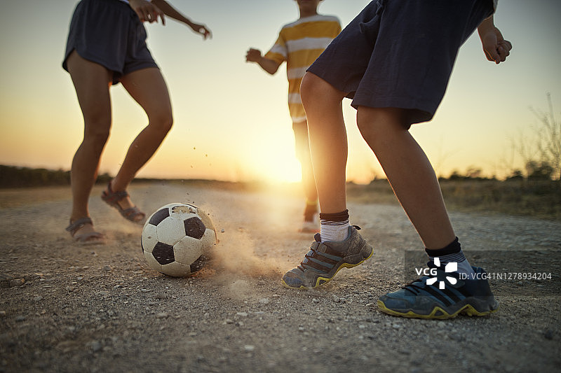 孩子们在土路上踢足球图片素材