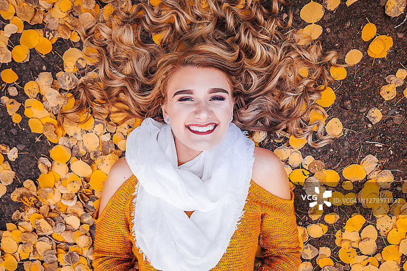 快乐的年轻白人女性在科罗拉多州大梅萨国家森林的秋色中仰卧图片素材