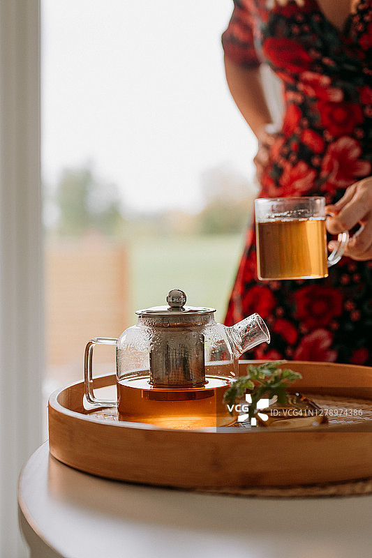 女人在茶道中将新鲜冲泡的茶倒入玻璃杯和茶壶图片素材