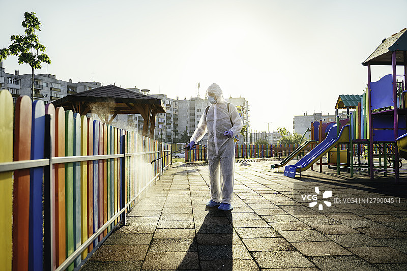 穿防护服的男人喷洒消毒剂，新冠疫情图片素材