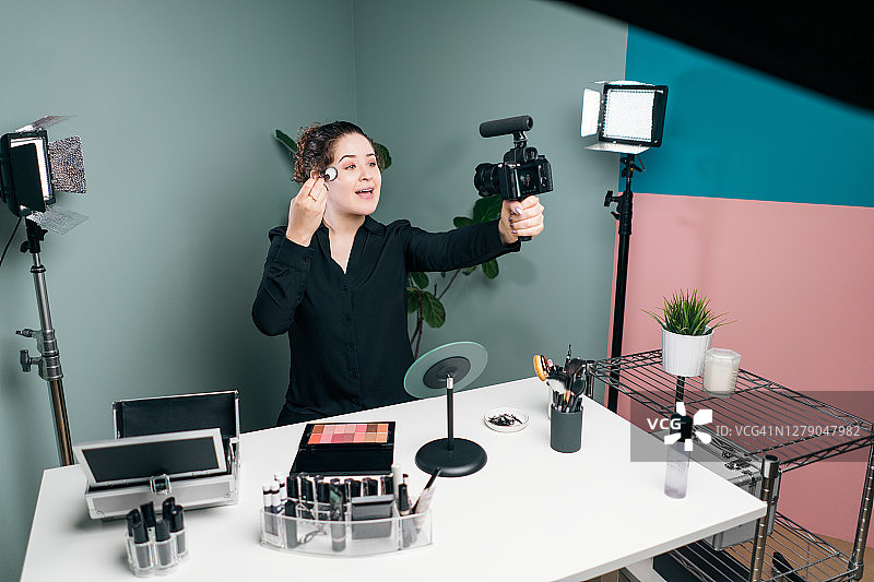 正在化妆并手持相机的女性视频博主图片素材