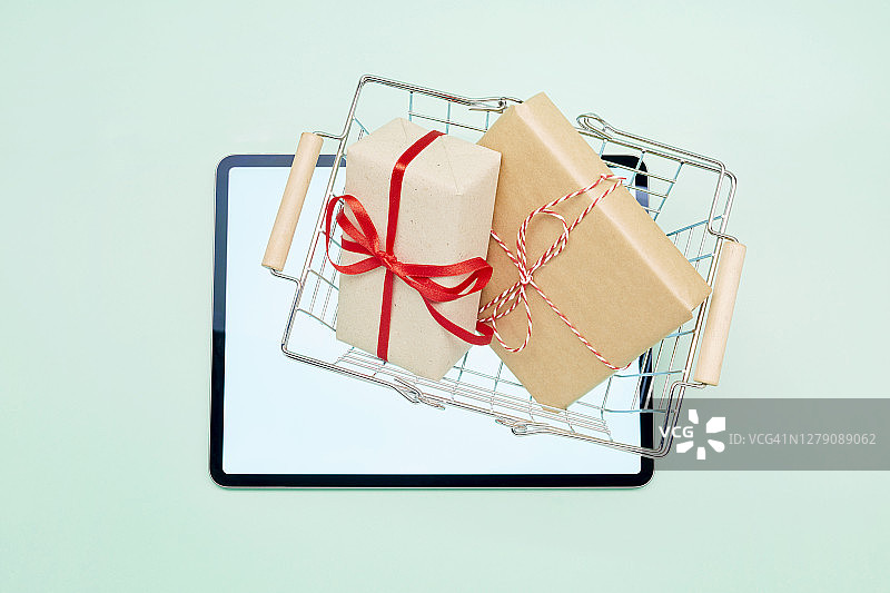 平板电脑上的购物篮和包裹的俯视照片，在线购物图片素材