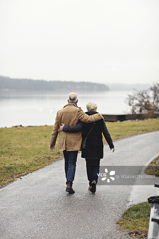 冬季，老年夫妇的背影，互相搂着走在小路上图片素材