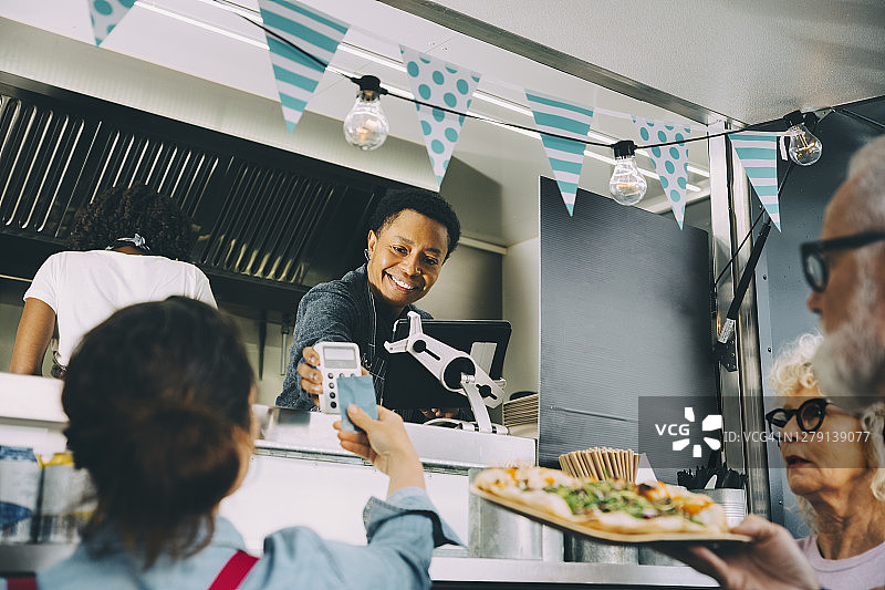 微笑的男店主在餐车里与顾客谈论非接触式支付图片素材